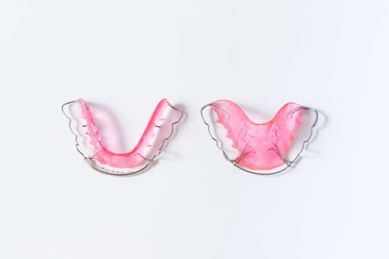 hawley retainer on white background. pink retainer teeths for dental patient.